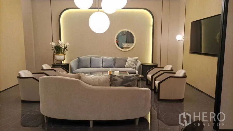 Retail Space for rent - Main lounge with sofas and armchairs around a coffee table, backlit wall and mirror.