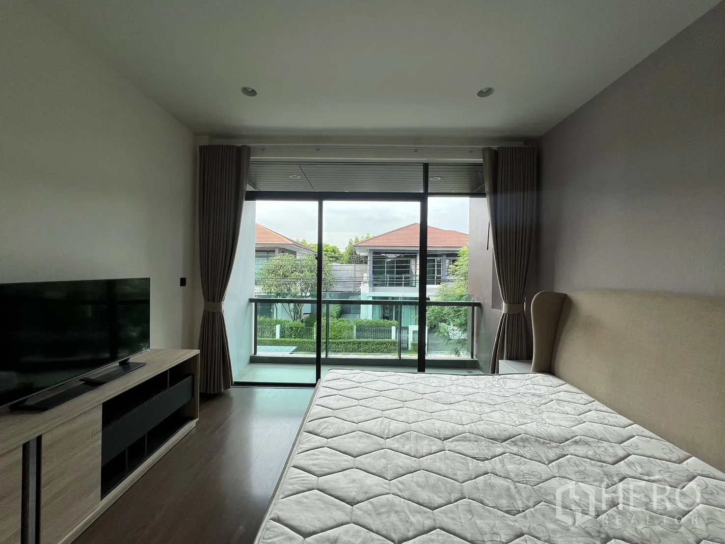 Detached House for rent in Bang Kapi, Bangkok - Master bedroom with balcony, bed and TV cabinet.