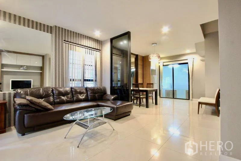 Townhouse for sale in Suan Luang, Bangkok - Bright open-plan living and dining area with leather sofa and glass coffee table.