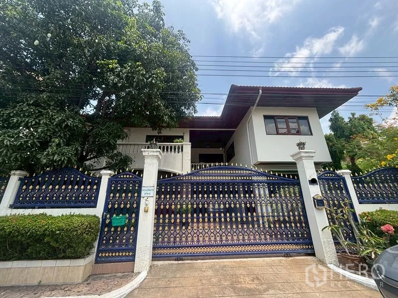 บ้านเดี่ยว for sale in Suan Luang, Bangkok - ด้านหน้าบ้านสองชั้นพร้อมประตูรั้วเหล็กดัดสีน้ำเงินลวดลาย