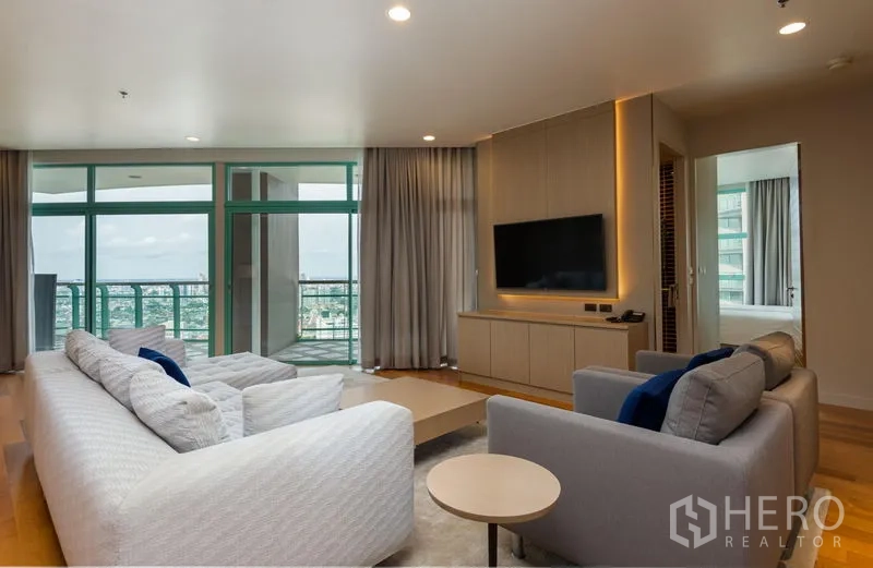 Condominium for rent in Bang Kho Laem, Bangkok - Living room with sofas, media wall and balcony doors opening to panoramic river and skyline views.