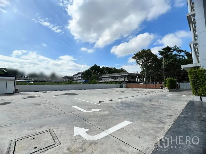 零售空间 出租在Huai Khwang, Bangkok - 室外大型停车场，划线车位与指示箭头，旁有绿化和蓝天。