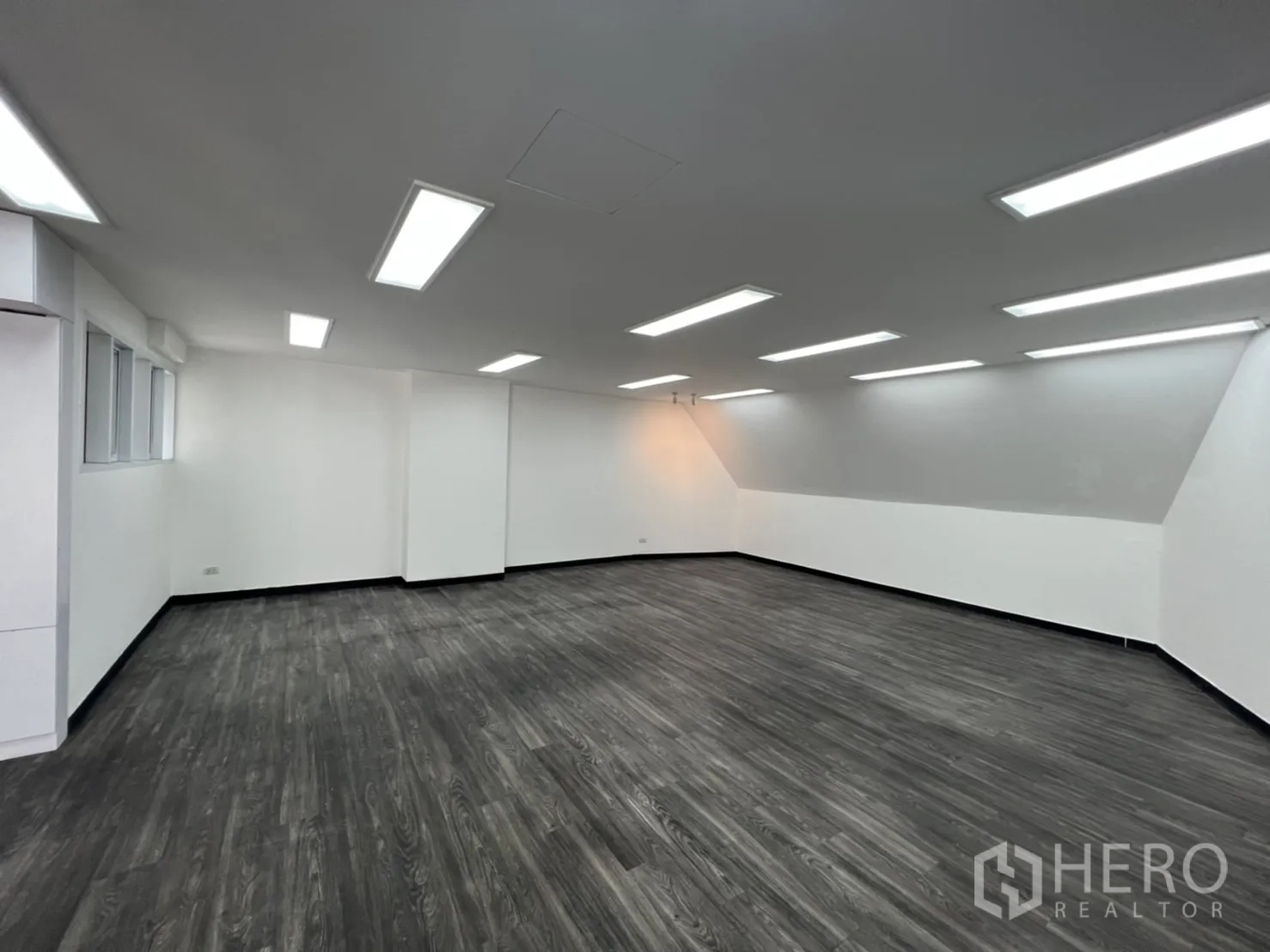 Retail Space for rent in Sathon, Bangkok - Open workspace with sloped ceiling, gray floors and bright LED panels.