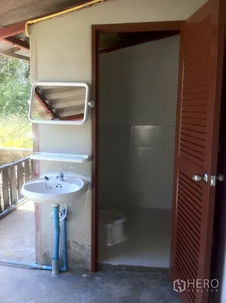 Warehouse for rent in Lam Luk Ka, Pathum Thani - Simple restroom with open door, wall mirror, sink, and toilet.