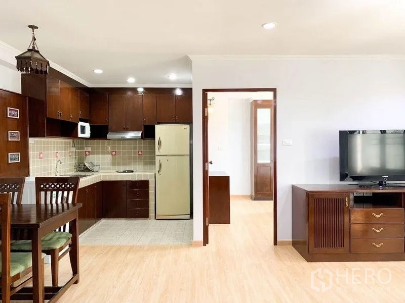Condominium for rent or sale in Khlong Toei, Bangkok - Kitchen with wooden cabinets, tiled backsplash and adjacent dining set.