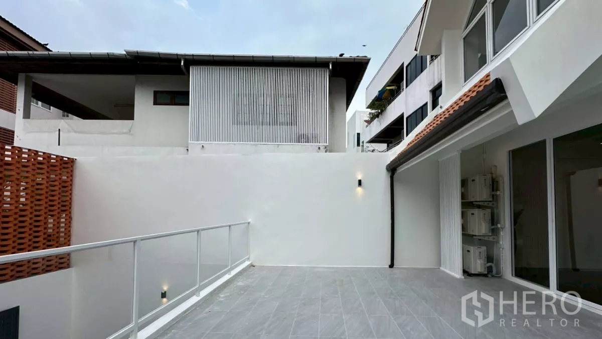 Home Office for rent in Watthana, Bangkok - Expansive upper terrace with white walls, glass railing and outdoor lighting.