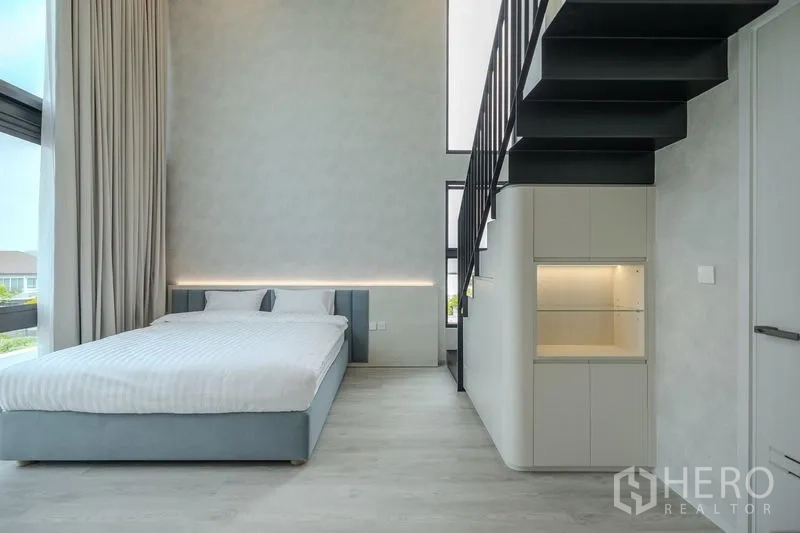 Detached House for rent in Saphan Sung, Bangkok - Double-height bedroom with mezzanine stair and minimalist decor.