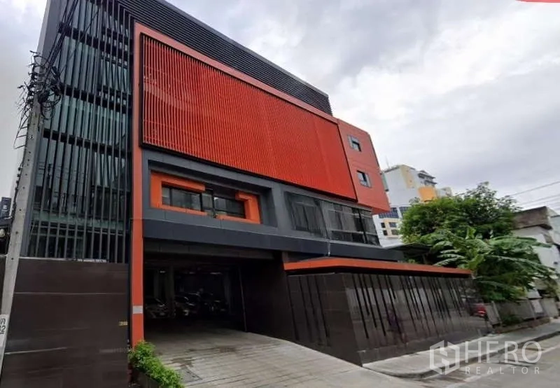 Retail Space for rent in Khlong Toei, Bangkok - Modern commercial building exterior with bold orange facade and a wide driveway entrance in Bangkok.
