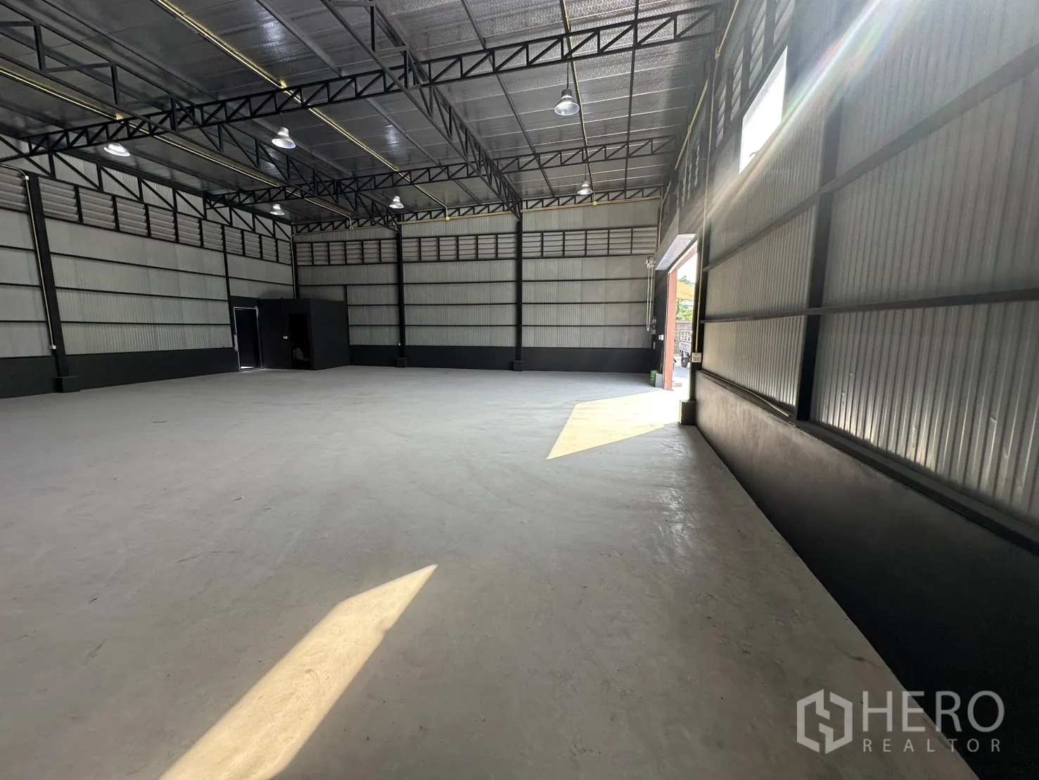 Warehouse for rent in Prawet, Bangkok - Long side aisle beside corrugated wall with sunlight streaming in near the entrance.