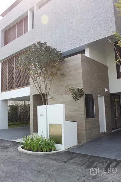 บ้าน ให้เช่าในHuai Khwang, Bangkok - ด้านหน้าบ้านเดี่ยวสไตล์โมเดิร์น 3 ชั้น พร้อมที่จอดรถและผนังไม้ผสมปูนกับสวนหย่อมทางเข้า