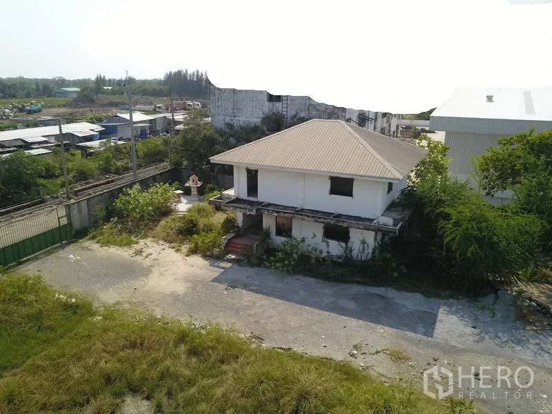 Factory for sale in Samut Prakan - Two-storey site office/house inside the industrial compound with driveway and trees.