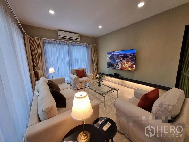 Detached House for rent in Bang Khae, Bangkok - Cozy family lounge with white sofas, lamps, glass coffee table and wall-mounted TV.