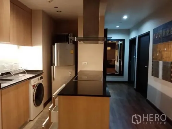 Condominium for rent in Sathon, Bangkok - Fitted kitchen with black granite countertops, induction hob, hood, fridge and washer-dryer.