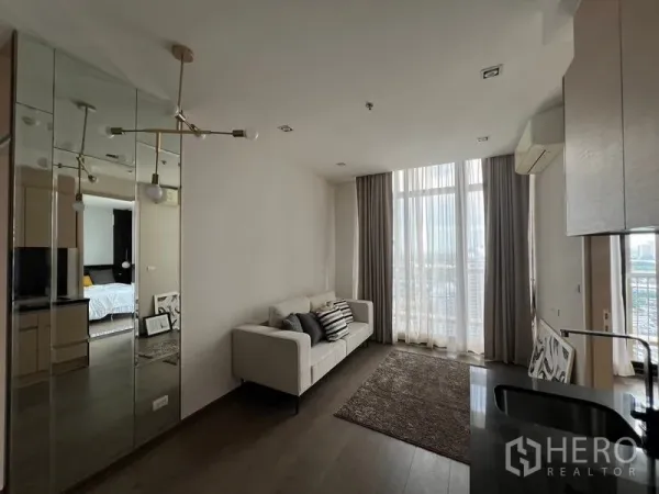 Condominium for sale - Bright condo living room with white sofa, floor-to-ceiling windows, mirrored wall and city view.