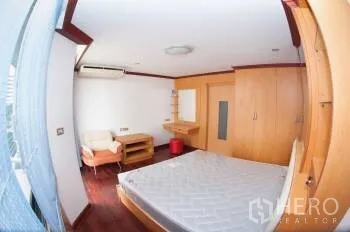Condominium for sale in Watthana, Bangkok - Bedroom from another angle showing a desk, large closet and air-conditioned space.
