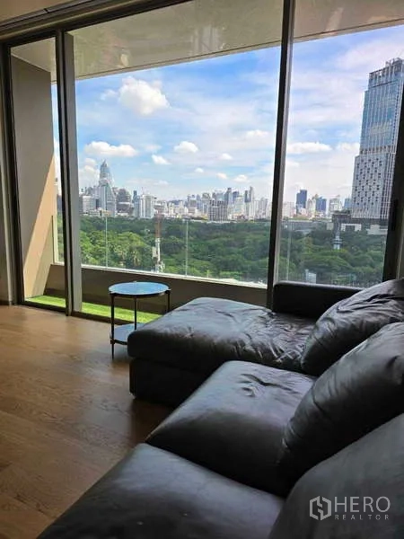 公寓 出租或出售在Bang Rak, Bangkok - 转角沙发靠落地玻璃，享受无遮挡的公园与高楼景致。