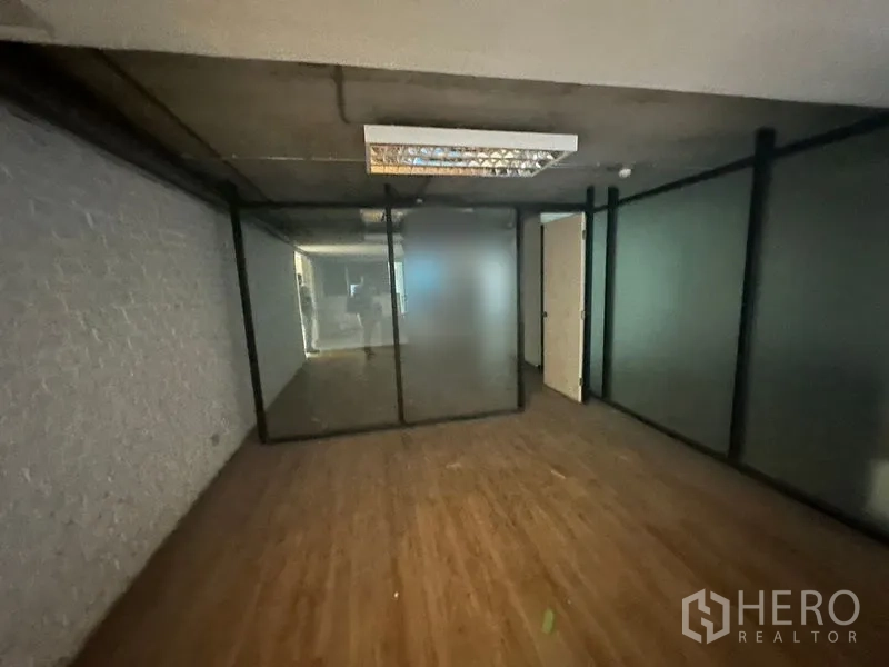 Office Space for rent in Khlong Toei, Bangkok - Enclosed office zone with frosted glass panels and exposed concrete ceiling lighting.