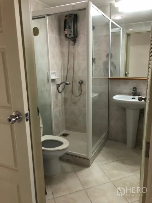 Condominium for rent in Watthana, Bangkok - Bathroom with glass shower enclosure, pedestal sink and toilet.