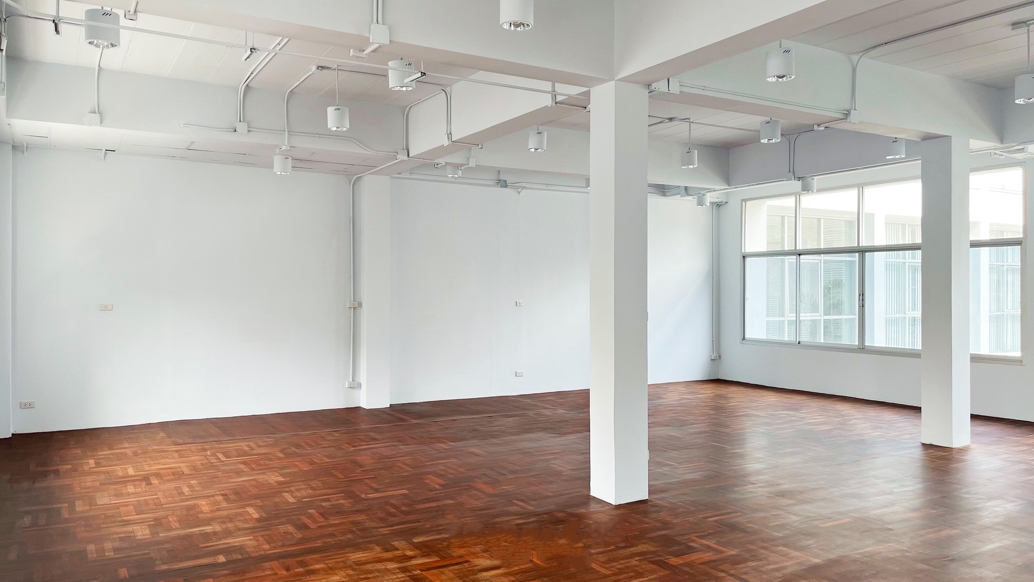Retail Space for rent in Watthana, Bangkok - Open-plan retail interior with parquet wood flooring, white columns, large windows and ceiling spotlights.