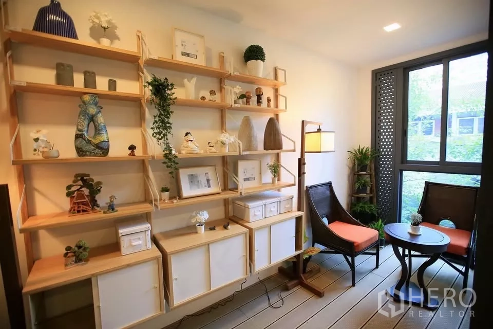 公寓 出租在Watthana, Bangkok - 整面木质展示架，窗边双人座与圆桌，面向花园景。