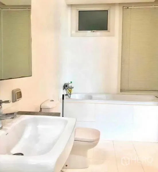 公寓 出租或出售在Ratchathewi, Bangkok - 明亮的浴室，白色調，配有浴缸、牆面鏡子、洗手台與馬桶。