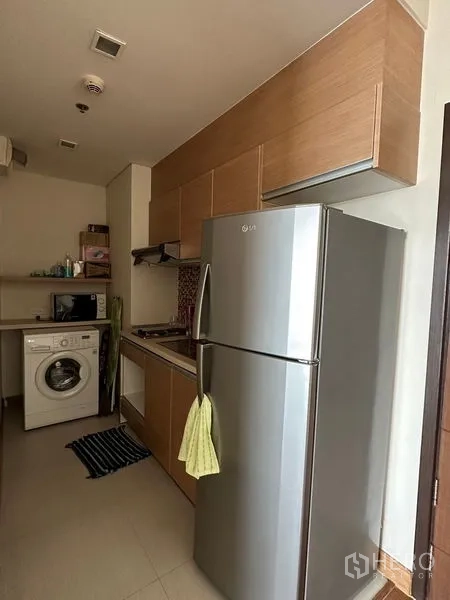 公寓 出售在Watthana, Bangkok - 紧凑厨房，木质橱柜、不锈钢冰箱和洗衣机。
