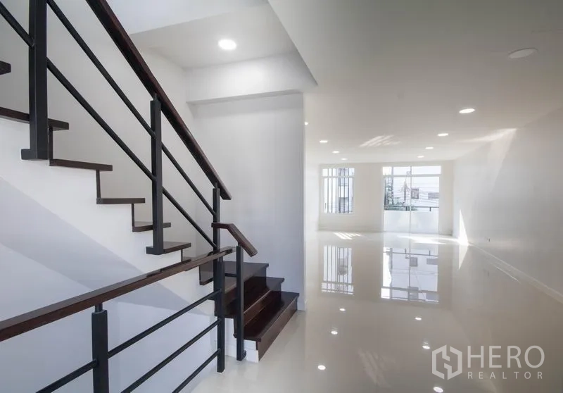 Home Office for sale in Huai Khwang, Bangkok - Staircase with metal railing leading to a bright open-plan office floor with windows.