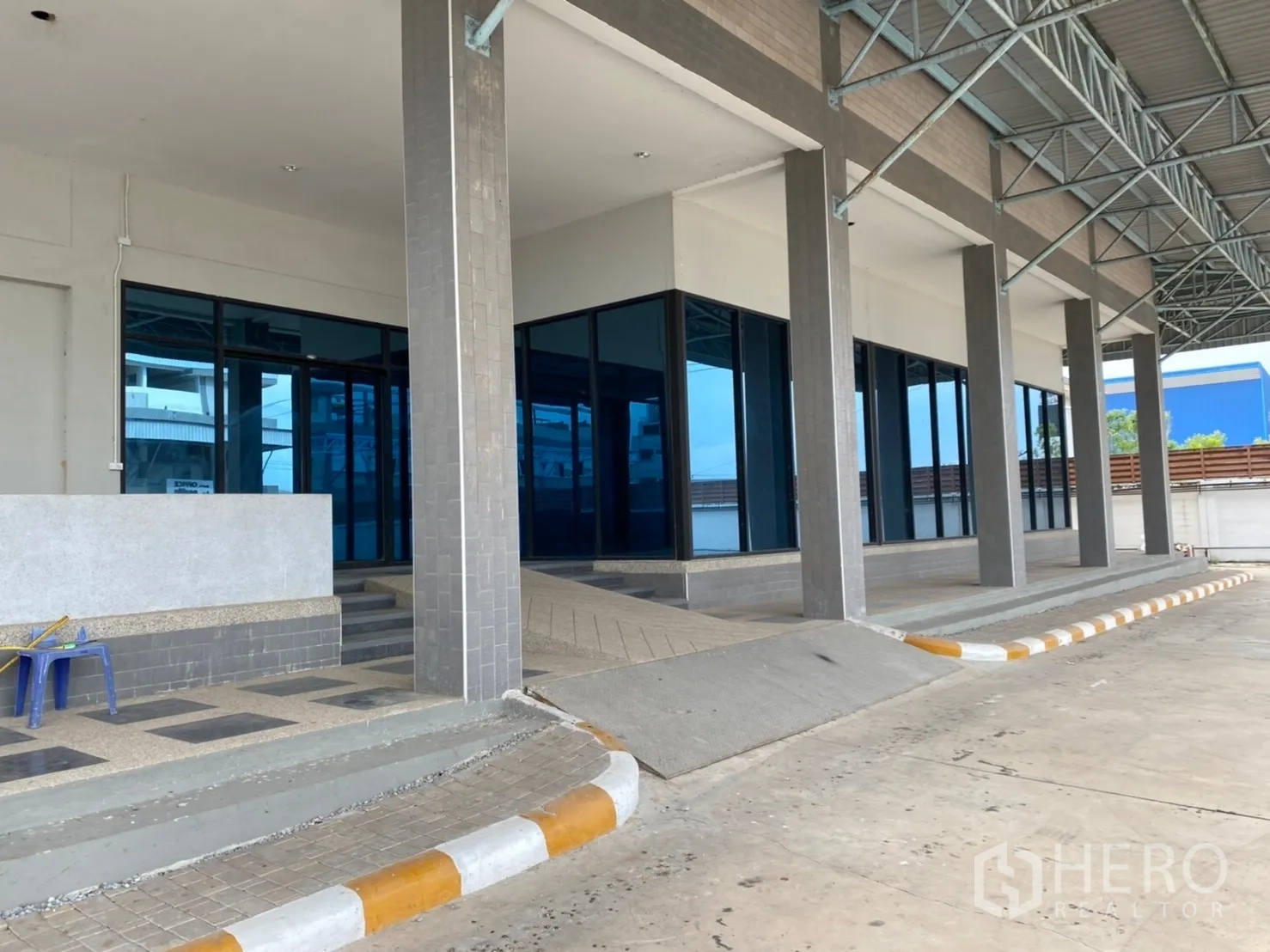 Warehouse for rent in Lat Krabang, Bangkok - Close-up of warehouse loading bay with ramp, glass-front offices and steel roof structure.
