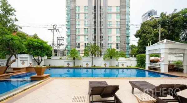 公寓 出售在Watthana, Bangkok - 室外游泳池配日光躺椅，绿植环绕与低密度公寓楼。