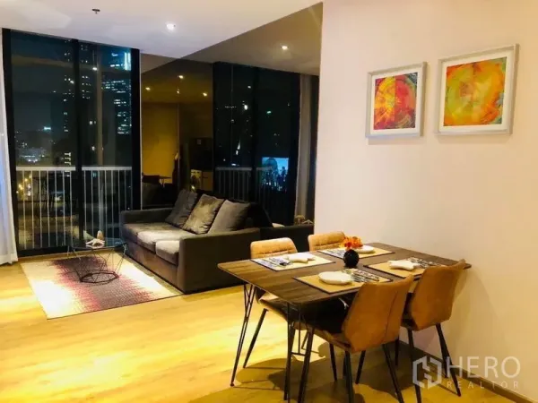 Condominium for rent in Khlong Toei, Bangkok - Another view of the open-plan living and dining space with sofa, dining set and night city outlook.