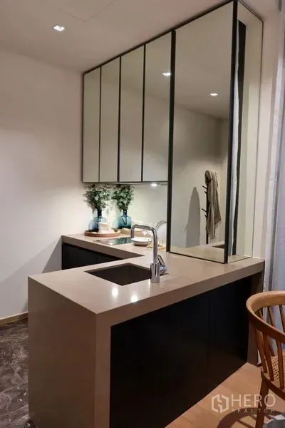 Condominium for rent in Pathum Wan, Bangkok - Modern kitchenette with stone countertop, under-mount sink and mirrored upper cabinets.
