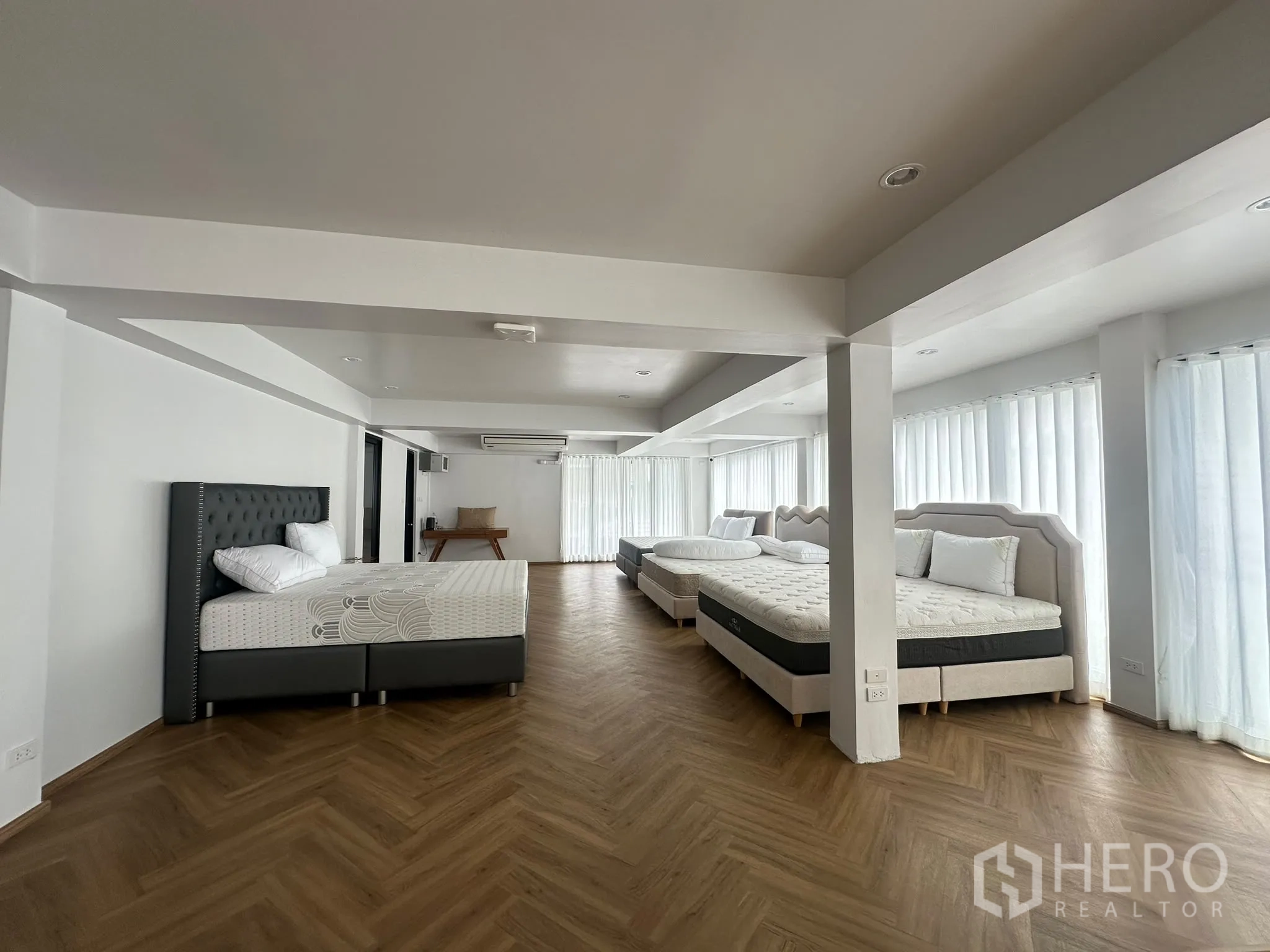 พื้นที่ขายของ for rent in Watthana, Bangkok - พื้นที่ชั้นบนแบบเปิดจัดวางเตียงหลายชุด ผนังสีขาว ผ้าม่านโปร่ง และพื้นไม้