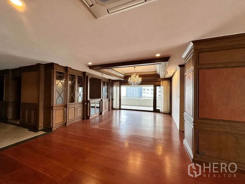 Condominium for rent in Bangkok - Open living room with chandelier and sliding doors to a wide balcony.