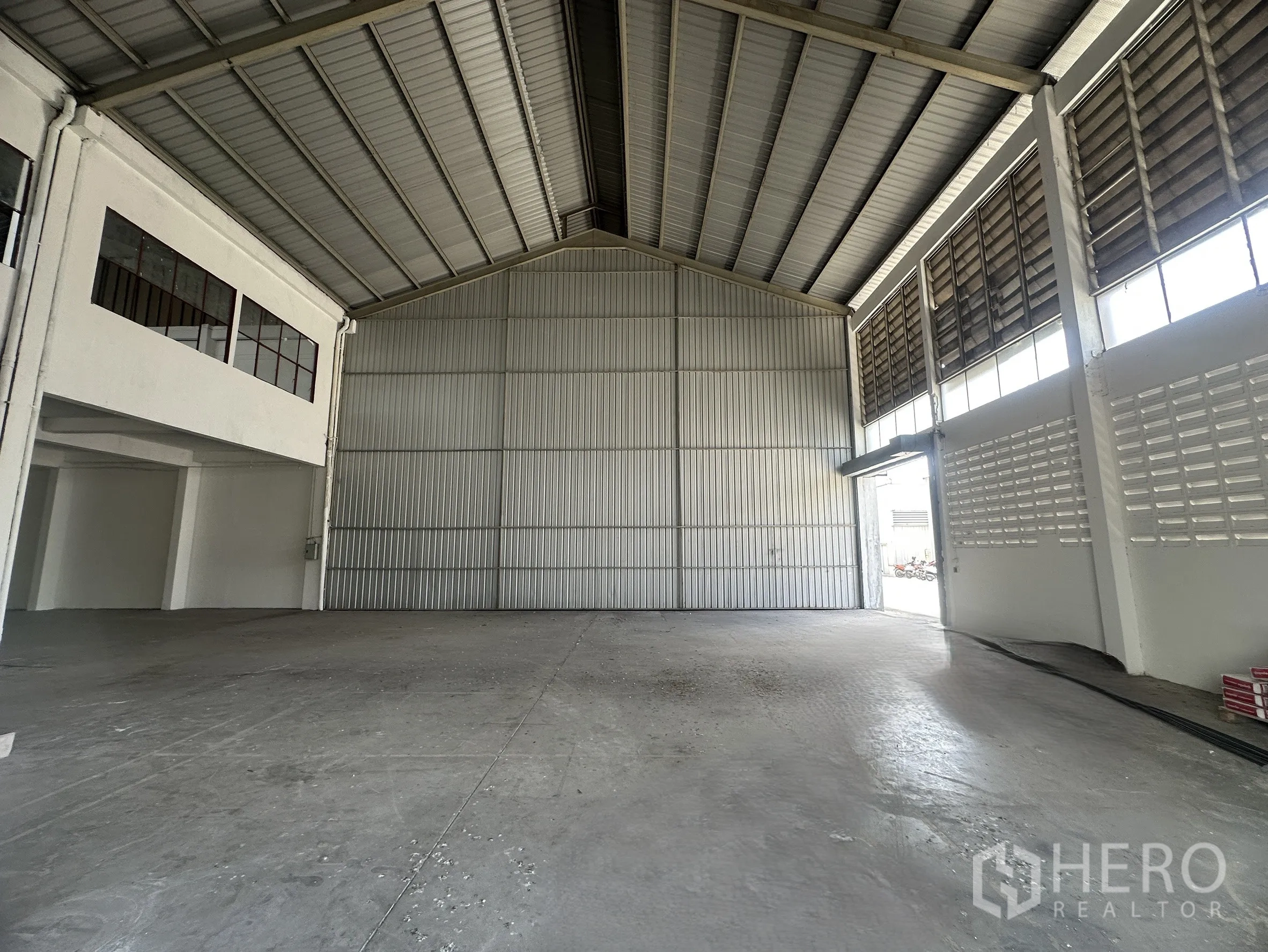 โรงงาน for rent in Mueang Samut Prakan, Samut Prakan - ภายในโรงงานกว้าง เพดานเมทัลชีทสูง พื้นคอนกรีต และประตูเหล็กบานเลื่อนสำหรับขนถ่าย