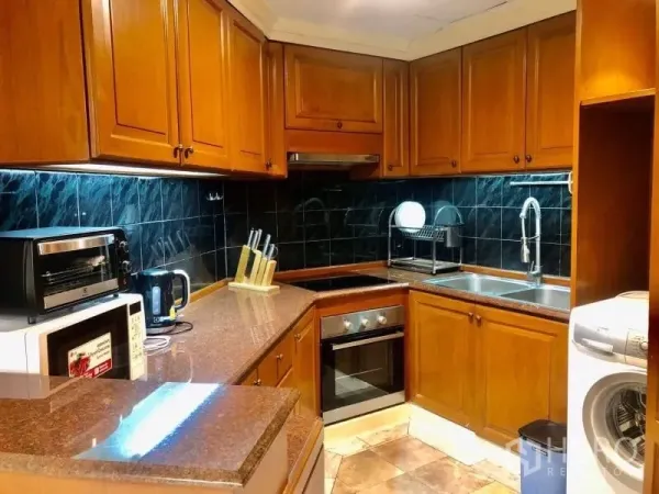 Condominium for rent in Watthana, Bangkok - U-shaped kitchen with wooden cabinets, stone countertops, oven and black tile backsplash