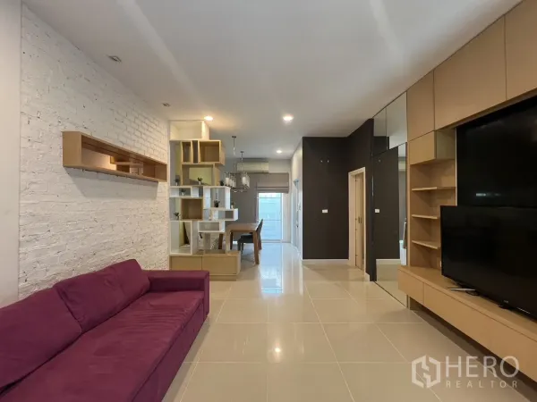 联排别墅 出租在Wang Thonglang, Bangkok - 开放式客厅，紫色沙发、内置电视墙与置物架。