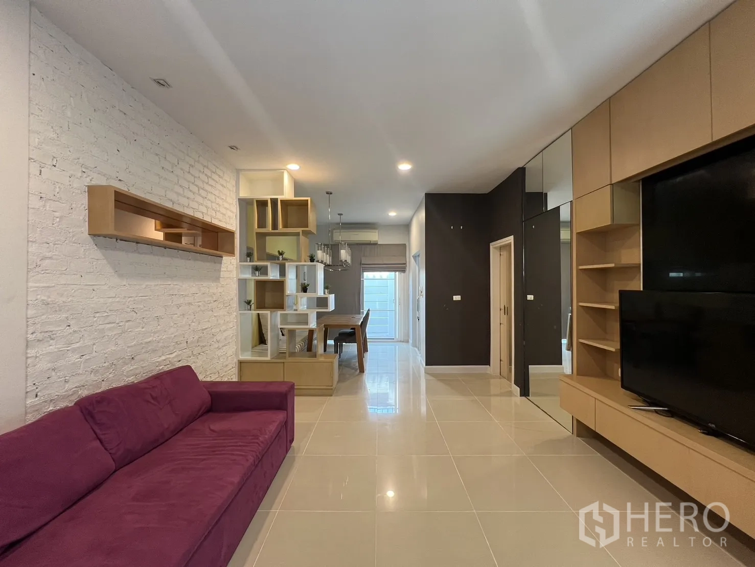 联排别墅 出租在Wang Thonglang, Bangkok - 开放式客厅，紫色沙发、内置电视墙与置物架。