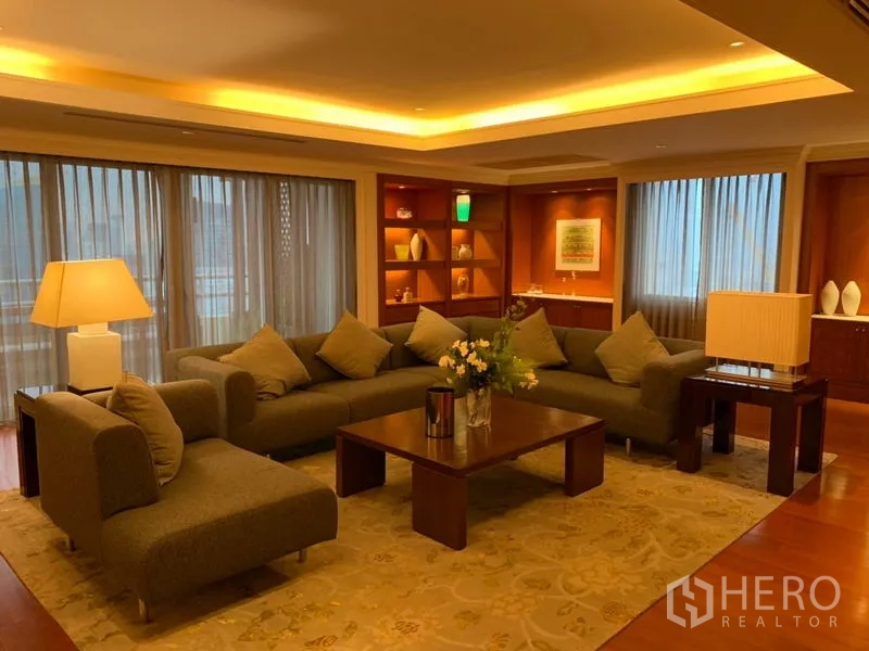 Condominium for rent or sale in Watthana, Bangkok - Cozy living room with L-shaped sofa, built-in display shelves and large windows.