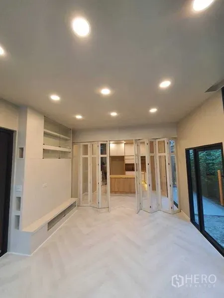 บ้าน ขายในPrawet, Bangkok - ห้องนั่งเล่นสว่าง เพดานฝังไฟ พื้นลายก้างปลา และประตูกระจกพับเชื่อมครัว