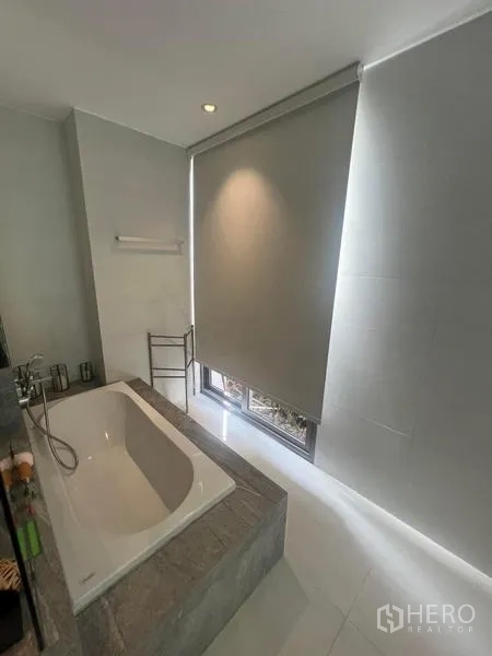 Townhouse for rent - Modern bathroom featuring a deep soaking tub beside a tall window