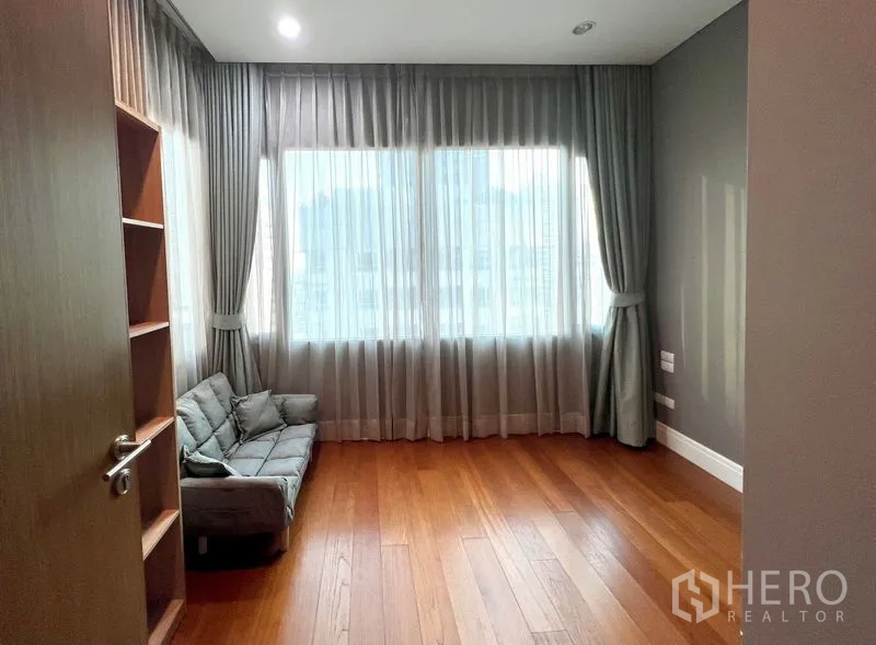 Condominium for rent in Khlong Toei, Bangkok - Spacious room with wooden floors and sheer-curtained windows, ideal as a bedroom or study.