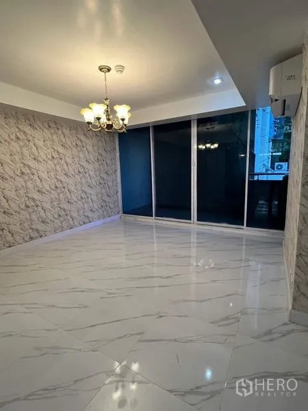 Condominium for rent or sale in Watthana, Bangkok - Bright room with sliding glass doors to a balcony and air-conditioning unit.