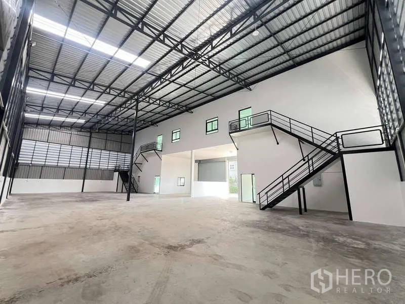 Warehouse for rent or sale - Expansive open‑plan warehouse with twin mezzanine staircases and high‑clearance roof trusses.