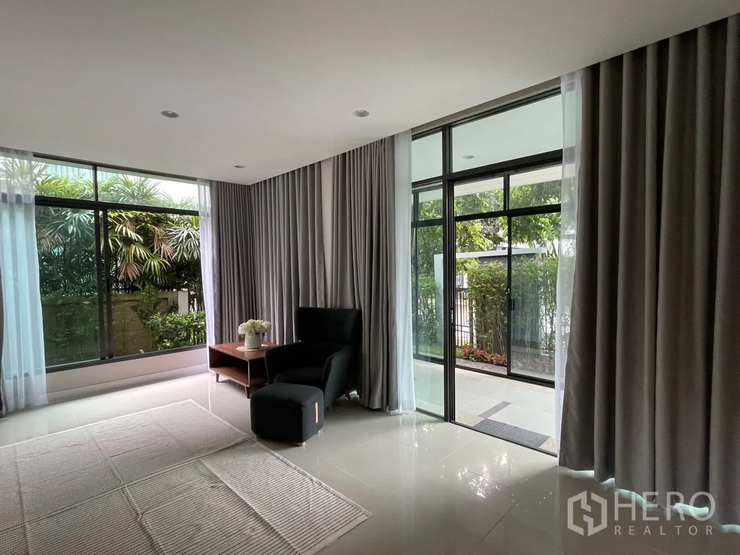 บ้าน ให้เช่าในBang Kapi, Bangkok - มุมห้องนั่งเล่นมีประตูกระจกบานเลื่อนไปยังชานหน้าบ้านและผ้าม่าน