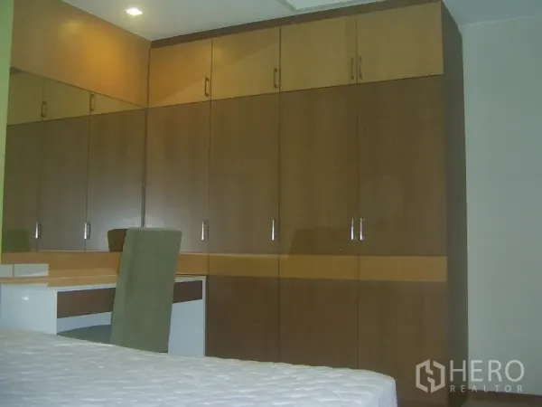 Condominium for rent in Khlong Toei, Bangkok - Wall of built-in wardrobes with a dressing table and chair in the bedroom.