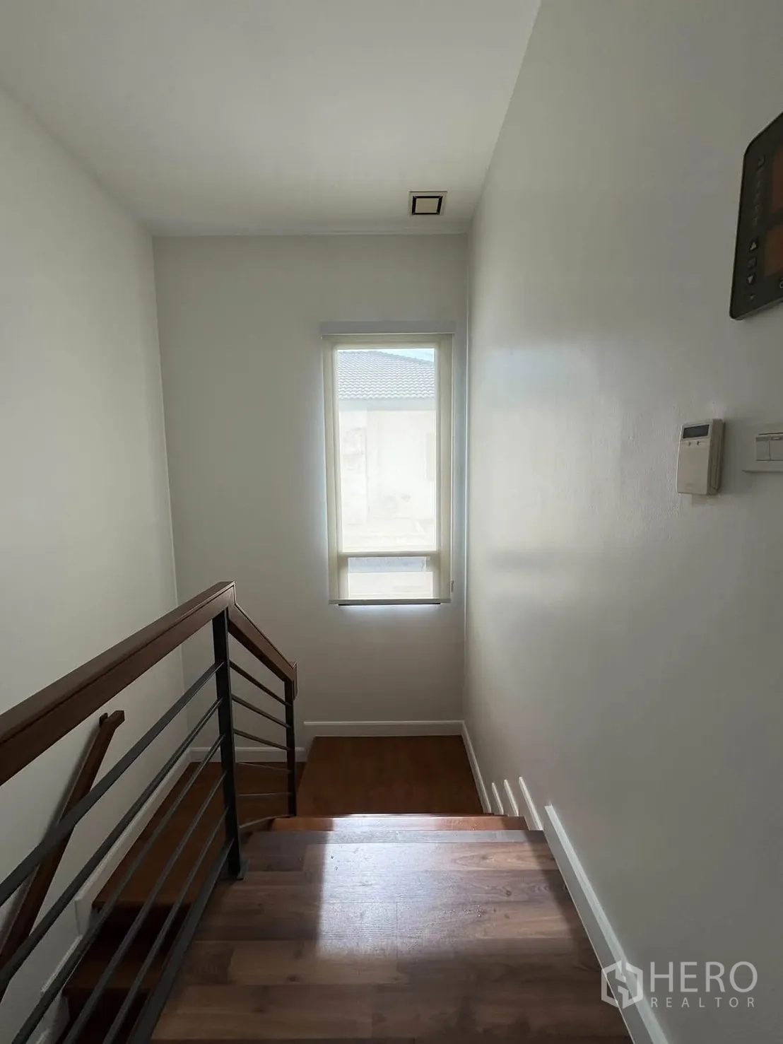 Detached House for rent in Prawet, Bangkok - Staircase with wooden steps, metal handrail, and a tall window providing natural light.