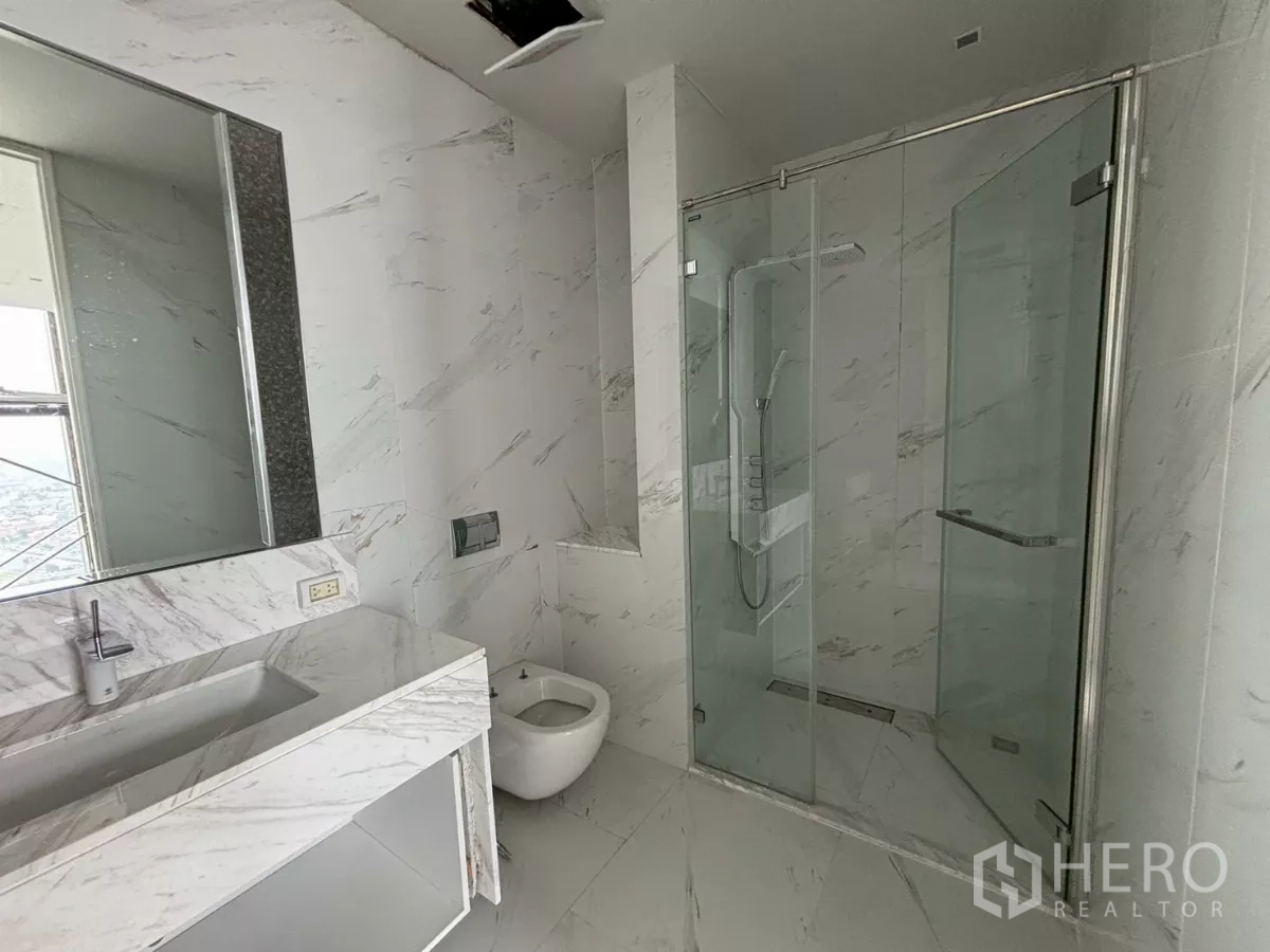 Condominium for sale in Bang Kho Laem, Bangkok - Modern marble bathroom with a glass-enclosed rain shower and vanity.
