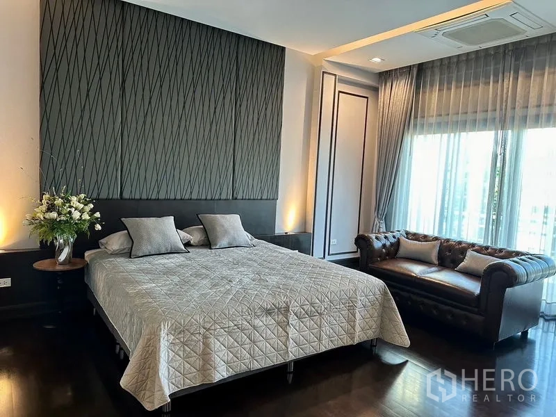 Detached House for rent - Primary bedroom with king bed, textured headboard, chesterfield settee and soft lighting.