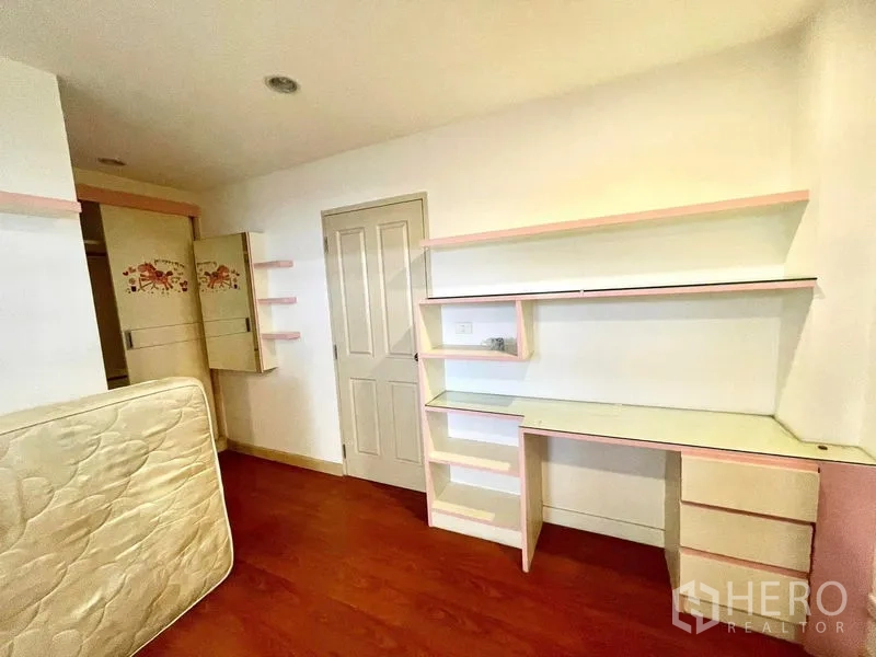 Townhouse for rent in Saphan Sung, Bangkok - Bedroom or study with long built‑in desk, pink‑trim shelving and warm wood floors.