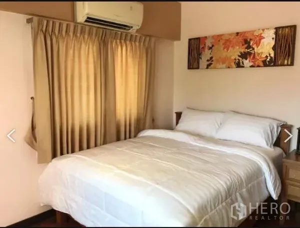 Detached House for sale in Saphan Sung, Bangkok - Cozy bedroom with double bed, beige curtains and wall art under an air conditioner.